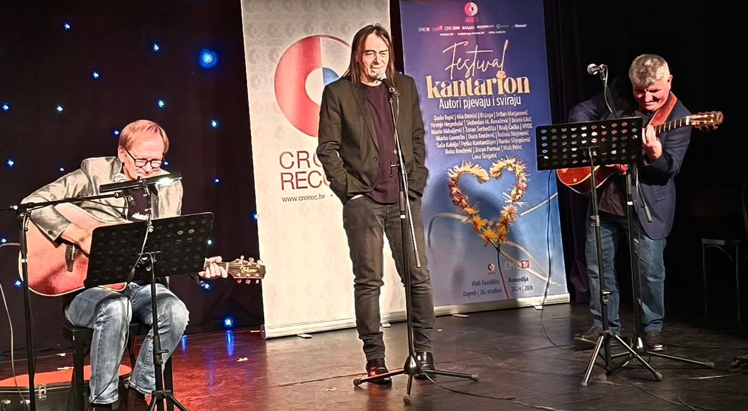 Young ballet dancers in pink tutus performing on a wooden stage under a slatted wooden ceiling